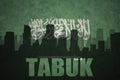 Abstract silhouette of the city with text Tabuk at the vintage saudi arabia flag