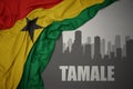 Abstract silhouette of the city with text Tamale near waving colorful national flag of ghana on a gray background