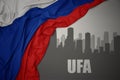 Abstract silhouette of the city with text Ufa near waving national flag of russia on a gray background Royalty Free Stock Photo