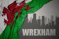 Abstract silhouette of the city with text Wrexham near waving national flag of wales on a gray background