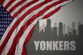 Abstract silhouette of the city with text Yonkers near waving national flag of united states of america on a gray background. 3D Royalty Free Stock Photo