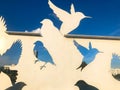 Abstract silhouettes of bird pigeons carved from metal in front of a blue sky