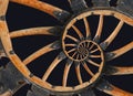 Abstract spiral wooden wagon cannon wheel with black metal brackets, rivets. Wheel wooden rim spokes background. Horse vehicle whe Royalty Free Stock Photo