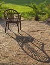 Abstract still life of chair in garden with shadow on stone paving