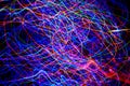 Abstract tangled lines on a black background represent the movements of electrons in their cosmic orbits. Christmas tree lights in