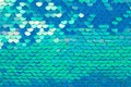 Abstract textured holographic background from turquoise shiny iridescent sequins, like mermaid or fish scales. Trendy texture with