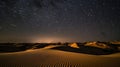 Abstract time lapse night sky with shooting stars over desert dune landscape. Milky way glowing lights background. Royalty Free Stock Photo