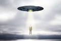 Abstract UFO with light taking businessman on sky background with mock up place. Spaceship and mystery concept Royalty Free Stock Photo