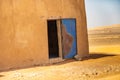 Abstract unreal picture of the corner of a house in the desert with an open blue damaged door of iron, Sudan Royalty Free Stock Photo