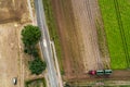 Abstract vertical aerial view of a narrow country road at the edge of an area of arable land with different coloured stripes