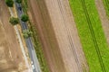 Abstract vertical aerial view of a narrow country road at the edge of an area of arable land with different coloured stripes Royalty Free Stock Photo