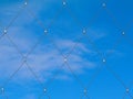 Abstract view of stainless steel mesh fence with clamps and blue sky background Royalty Free Stock Photo