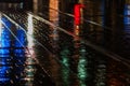 Abstract, wet pavement illuminated at night by colorful lights