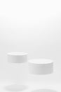 Abstract white scene mockup - two round white cylinder podiums, soar in hard light, shadow.