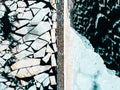 Abstract winter ice background texture of cracked frozen river water surface and floating ice pieces stone pier from above Royalty Free Stock Photo