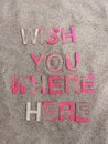 Abstract wish you were here written on sand and partially covered by sand Royalty Free Stock Photo