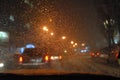 Abstraction. Blurred night urban view with cars, bright traffic lights through wet car windshield in blurred rain drops Royalty Free Stock Photo