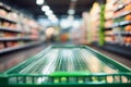 Abstractly blurred grocery store aisle with an empty green shopping cart