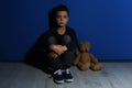 Abused little boy with toy near wall. Domestic violence concept