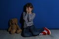 Abused little girl crying near wall. Domestic violence concept