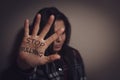 Abused teen girl showing palm with message STOP BULLYING near wall, focus on hand