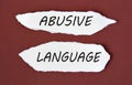 ABUSIVE LANGUAGE - words on white torn pieces of paper on a burgundy background Royalty Free Stock Photo