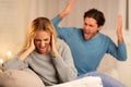 Aggressive Man Shouting At Woman Sitting On Sofa At Home
