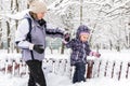 Aby girl with mother in winter park. Happy family walks during snowfall in Moscow, Russia Royalty Free Stock Photo