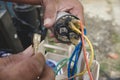 An AC technician removes a defective capacitor from a window type air conditioner control panel