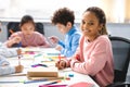 Smiling african american school girl sitting at desk in classroom Royalty Free Stock Photo