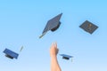 Academic hats and arm of student against blue backdrop Royalty Free Stock Photo