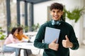 Academic success. Portrait of smiling european male student standing in modern classroom and showing thumbs up