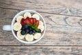 acai bowls with fresh fruit strawberry, blueberry, banana in white bowl on wooden table.