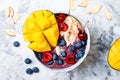 Acai breakfast superfoods smoothie bowl with mango, blueberry, cherry, coconut flakes. Overhead, top view