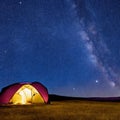 Camping tent in open field. Camp overnight. Camping tent with light on at night