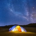 Camping tent in open field. Camp overnight. Camping tent with light on at night