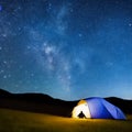 Camping tent in open field. Camp overnight. Camping tent with light on at night