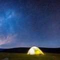 Camping tent in open field. Camp overnight. Camping tent with light on at night