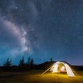 Camping tent in open field. Camp overnight. Camping tent with light on at night