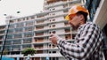 Acceptance of construction works. A man in a hard hat holds a construction plan in the phone. The man checks the conformity of the Royalty Free Stock Photo