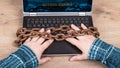 Close-up of hands, laptop keyboard and old rusty chains on wood background Royalty Free Stock Photo