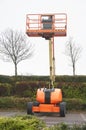 Access platform equipment powered high in sky in orange for high working platform height safety at construction building