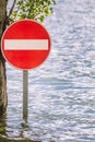 Access prohibition road sign partially submerged in a flood