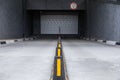 Access to underground car park with roller-shutter door and road dividers with yellow sticks