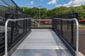 Accessible wheelchair ramp with railings and slip resistant surface at empty metal stadium bleacher.