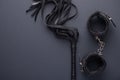 Accessories for bdsm on a black background. Leather lash and leather handcuffs. Valentine`s Day. Erotic shop. Copy space