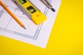 Accessories and drawing tools lie on building project or on the yellow desktop