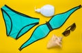 Accessories for the resort on the beach on a yellow background. Swimsuit, sunblock, sunglasses, shell. Top view Royalty Free Stock Photo