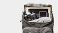 Accessories for travel. Camera, smartphone, tablet and other objects in the backpack over gray background.