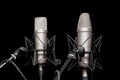 Two professional silver studio microphones on stands on black background, podcasting, voiceover. Interview or sports event